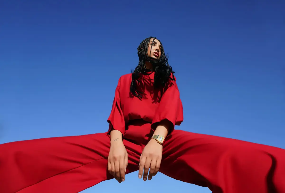 Editorial fashion model in red outfit against blue sky